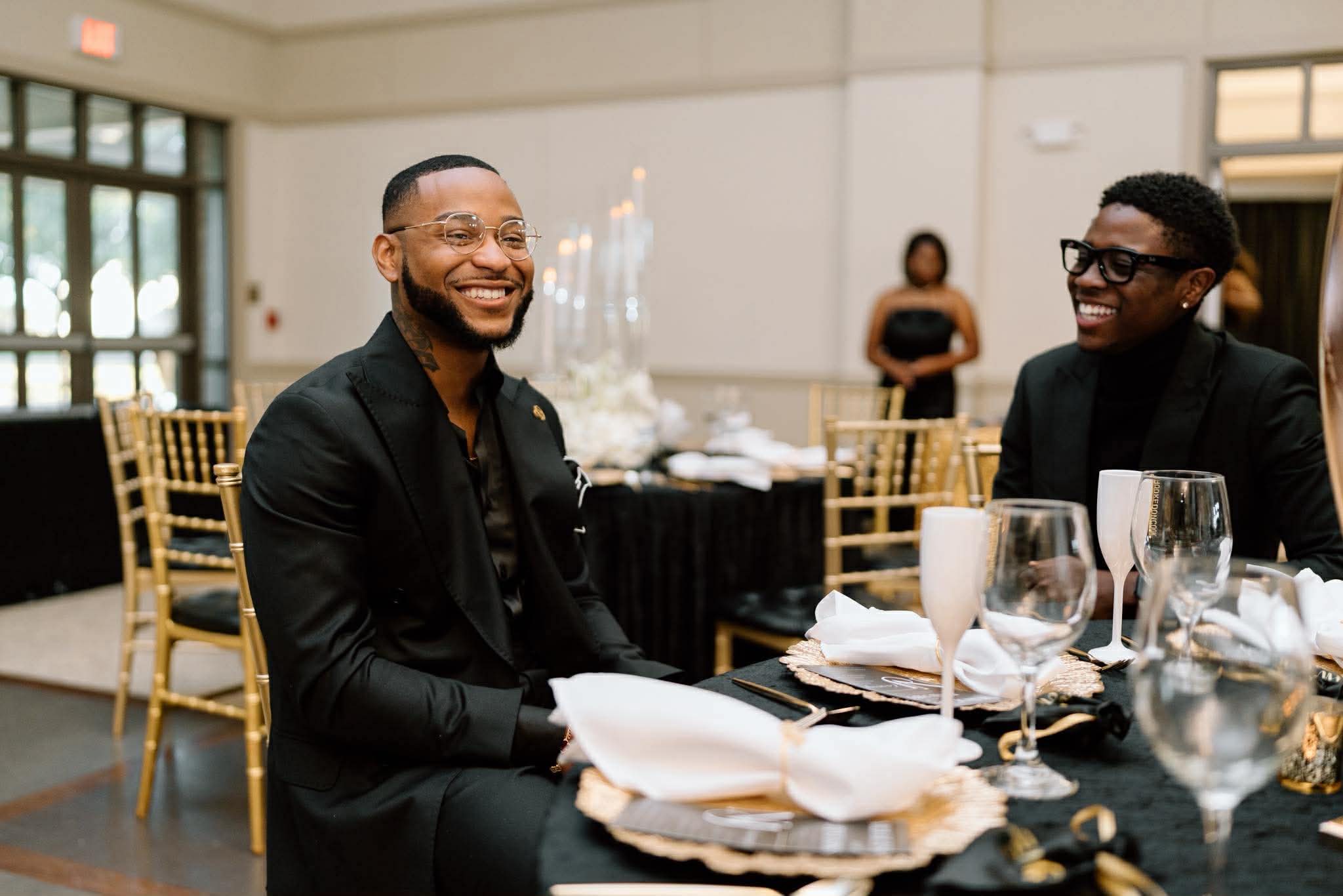 Two men in bespoke black suits at a formal dinner
