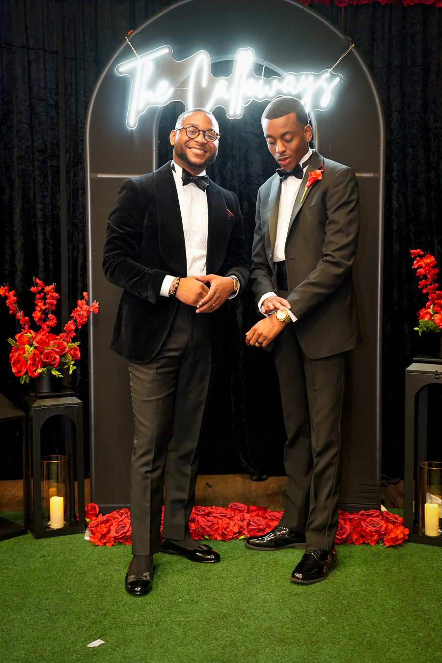 Two men in bespoke tuxedos at ceremony arch