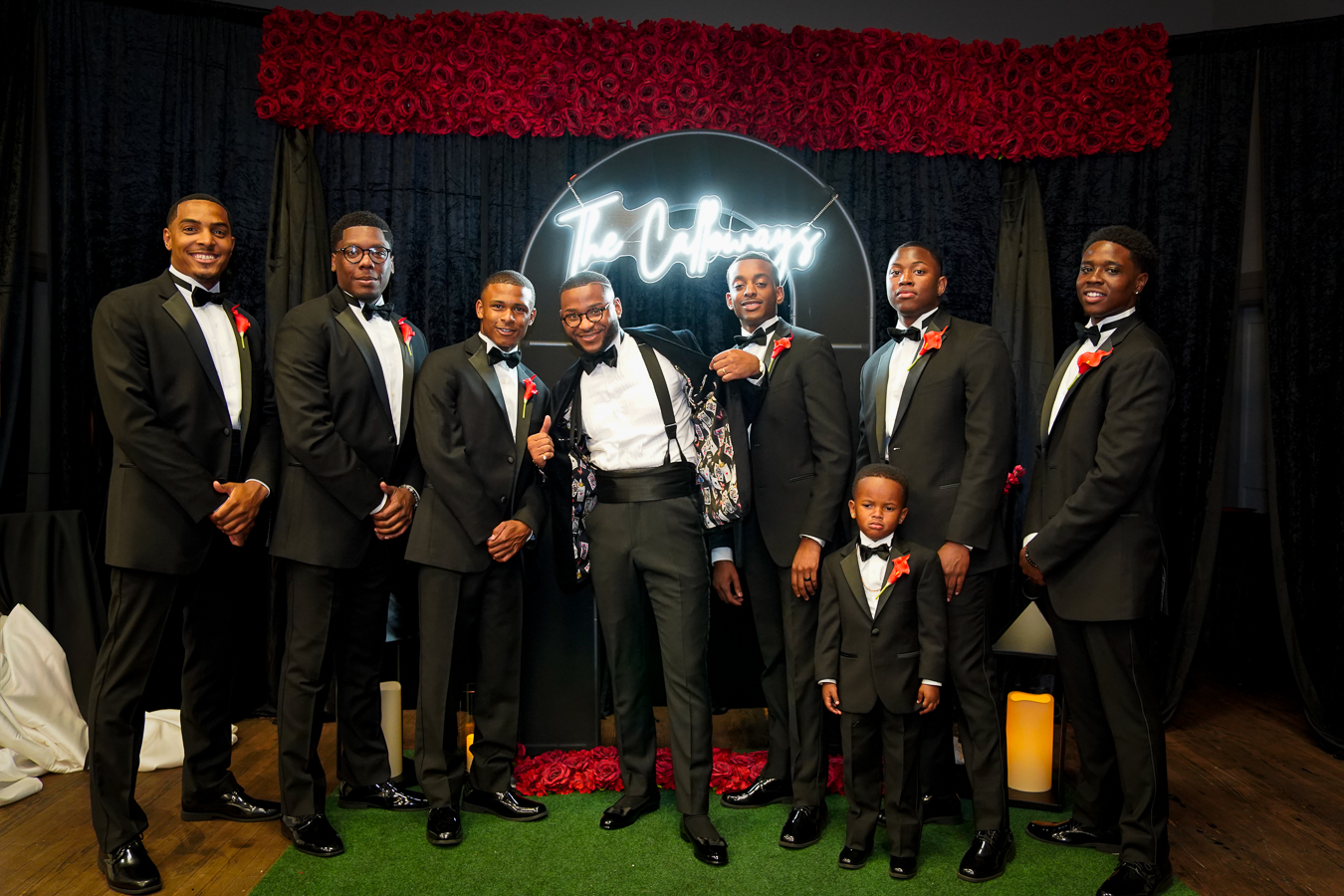 Groomsmen in black tuxedos at the reception venue