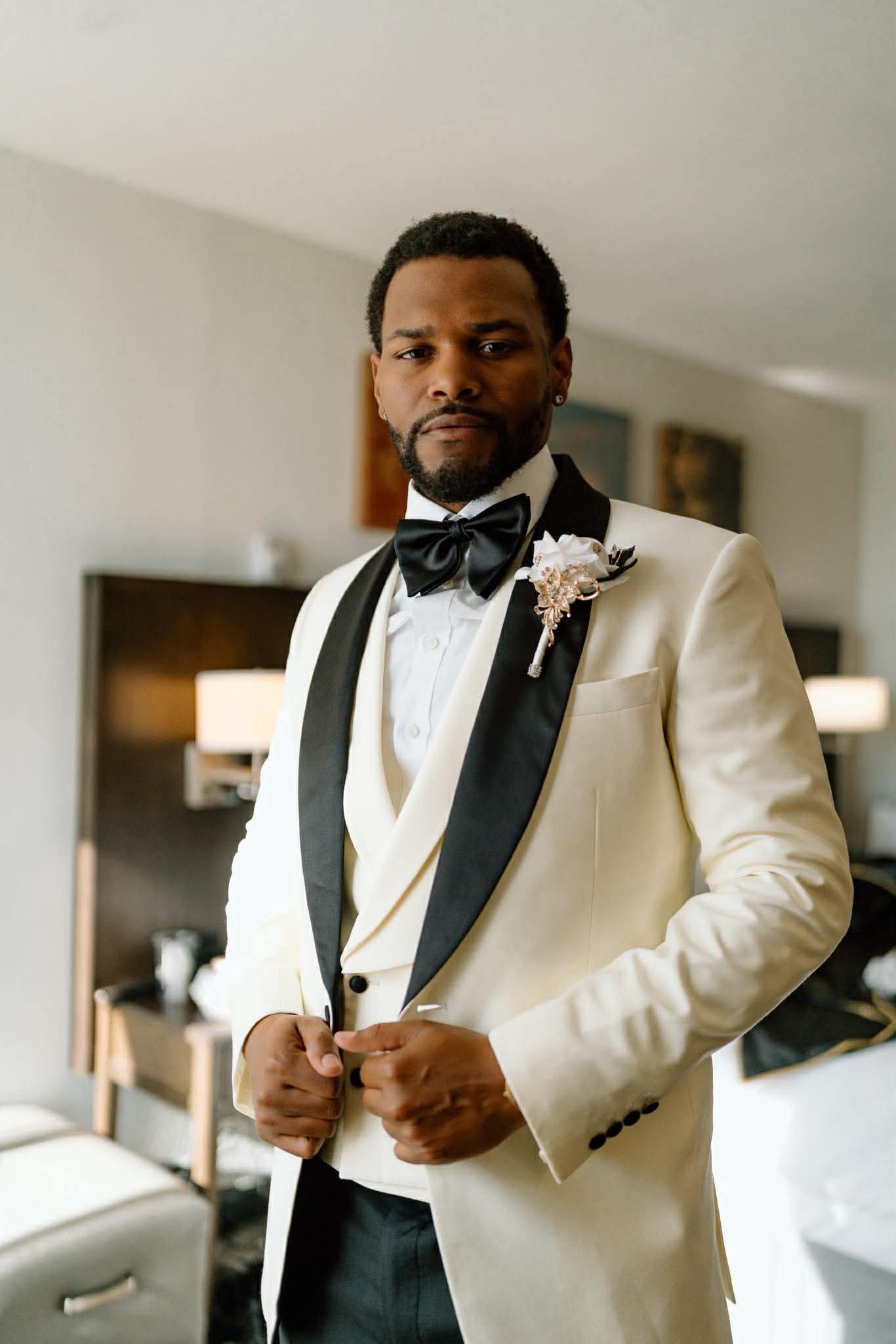 Groom in ivory tuxedo with black shawl lapel getting ready